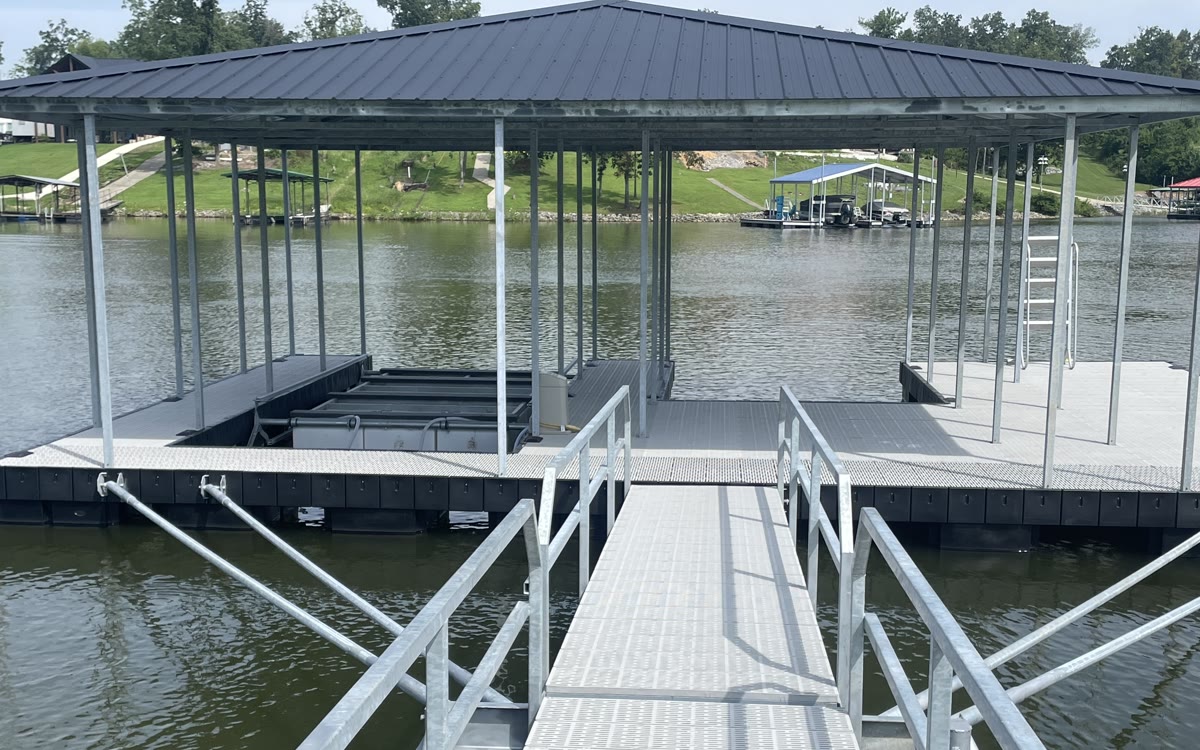 A covered Twin Lakes boat slip with a dark hip roof, gangway, swim ladder and wide walk-around decking