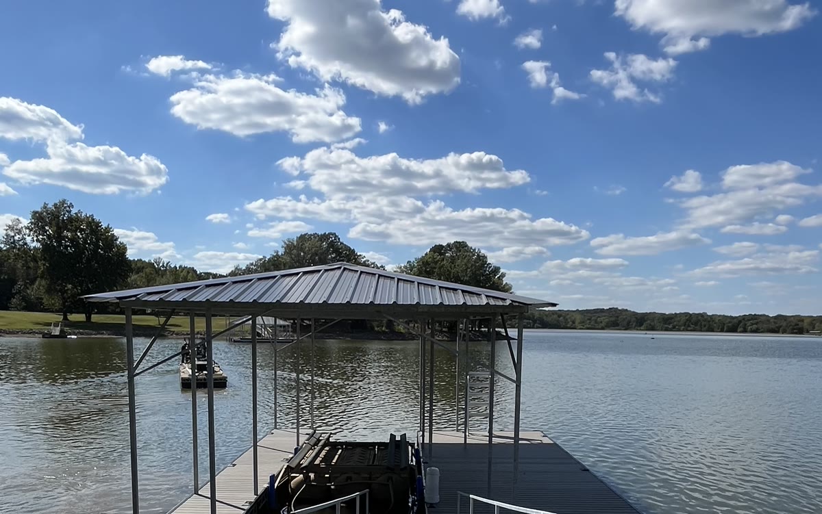 A Twin Lakes boat slip with a galvanized hip roof on open water under a blue sky